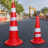 Red and white traffic safety cones on a road construction site with barricades and excavator in the background.